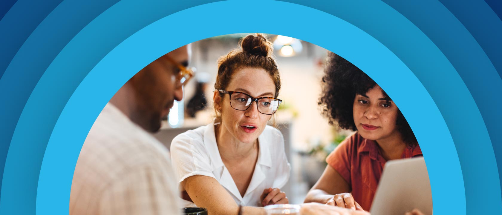 A man and two women looking at a laptop screen together