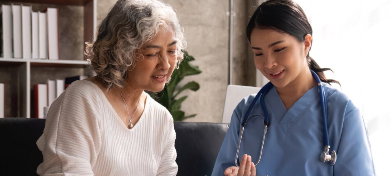 A doctor smiling while reading a medical chart with a patient