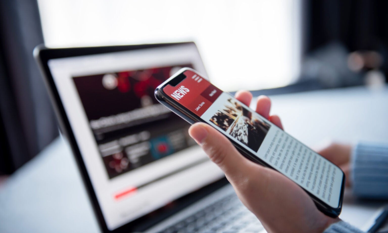 person holding a phone with news on screen