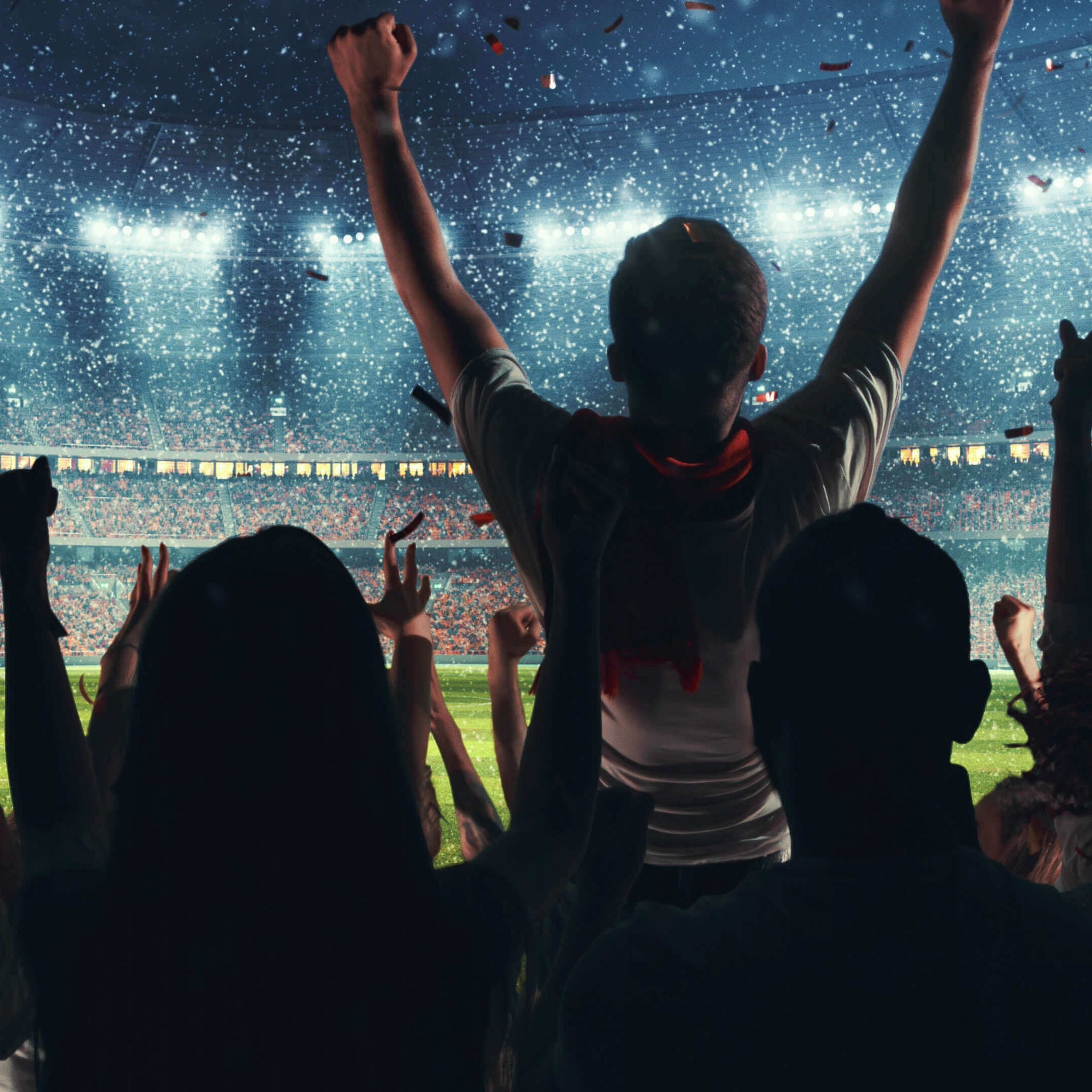 Sports fans cheering in the crowd with their arms in the air