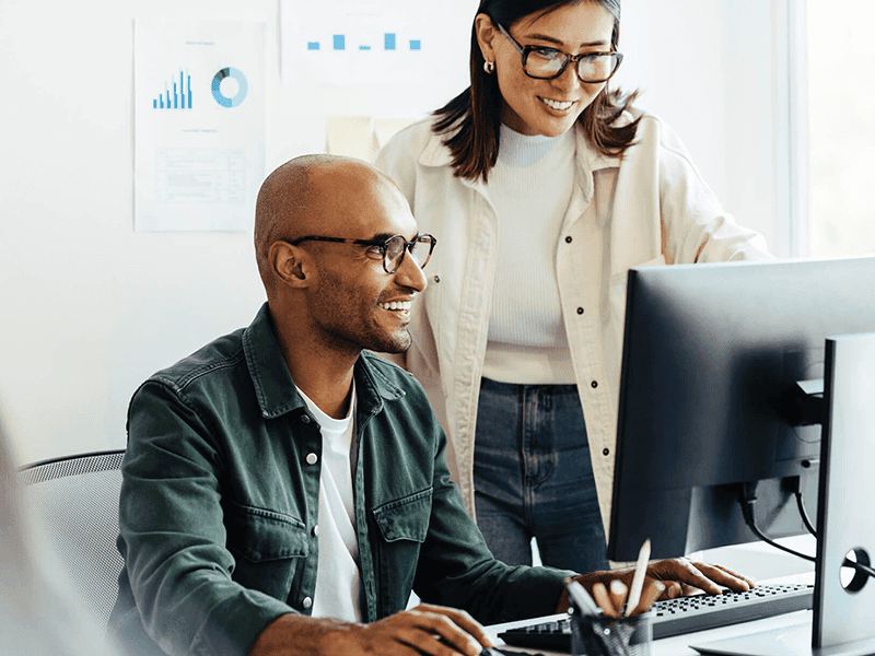 Two coworkers looking at a computer together