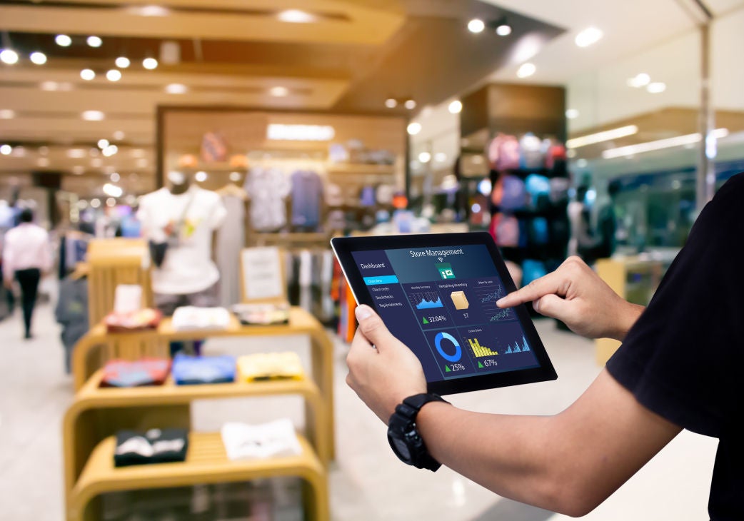 image of a hand resting on a laptop with a phone in the other hand