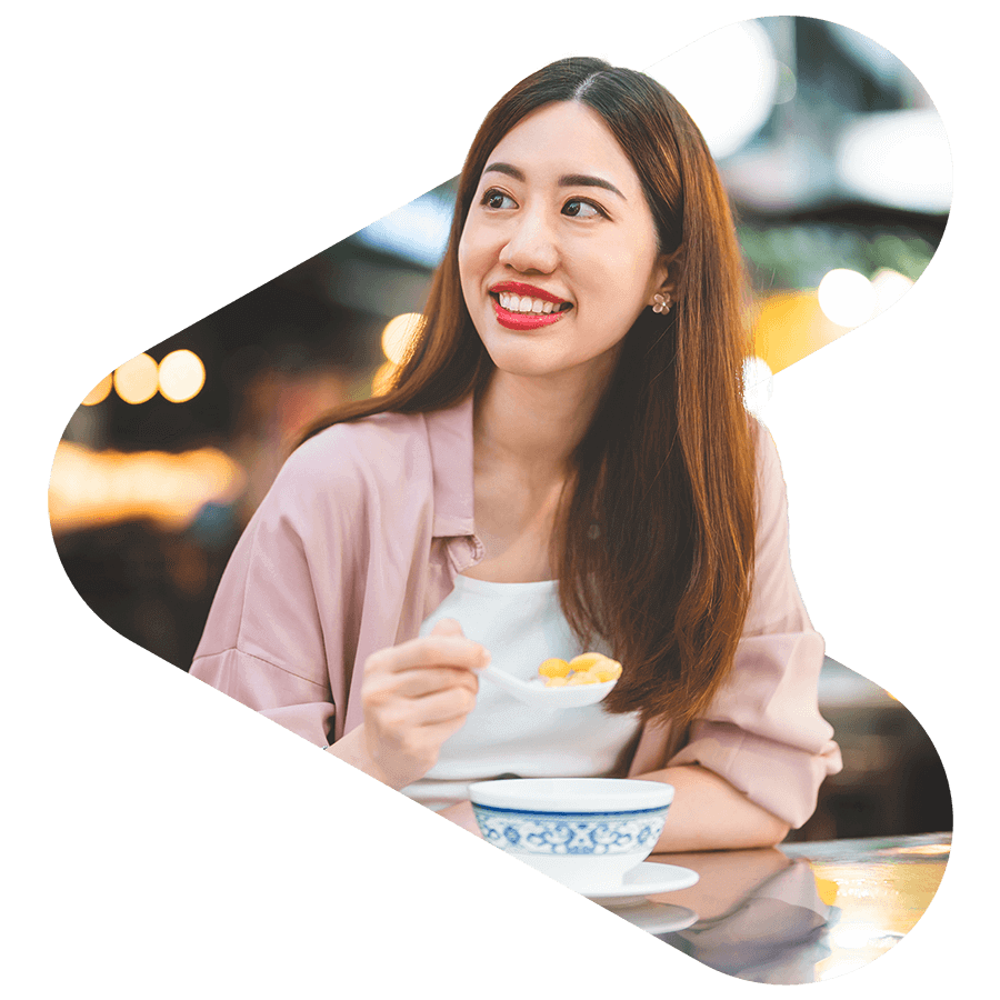 woman smiling while eating a bowl of cereal