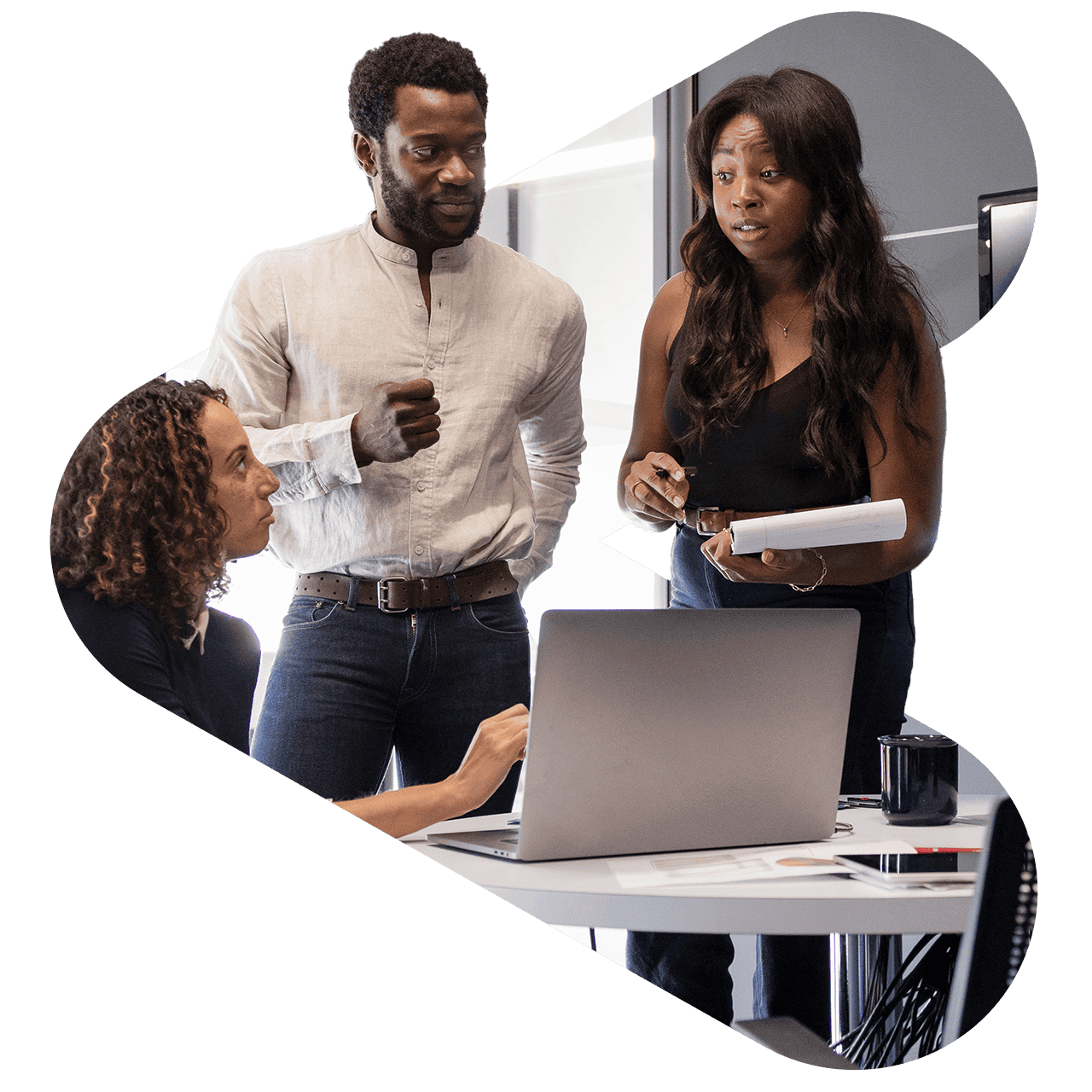 Three marketers having a collaboration session in front of a desk with an open laptop