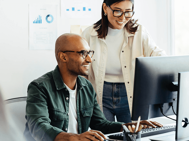Two coworkers looking at a computer together
