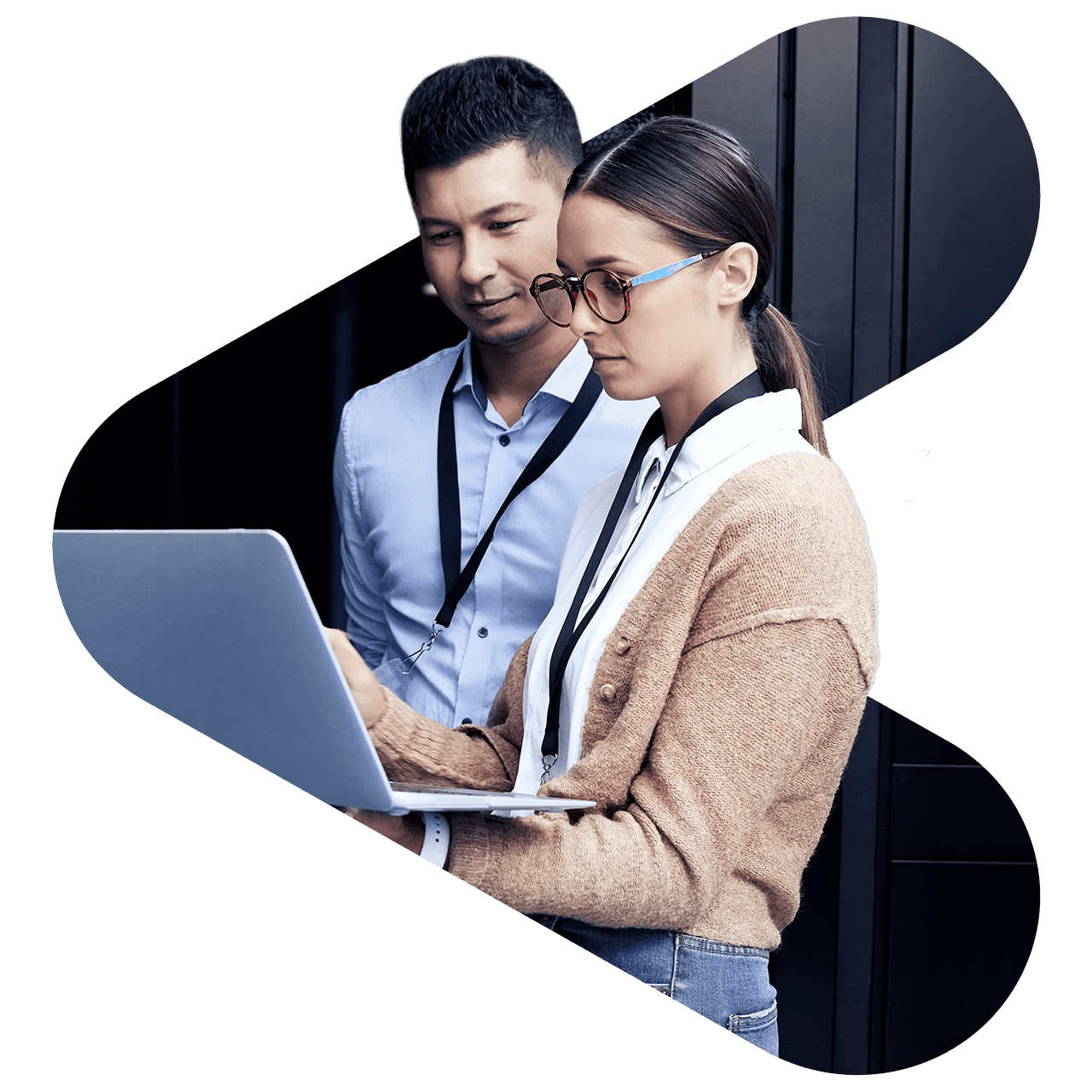 a man and a woman standing, staring at a laptop in the woman's left arm
