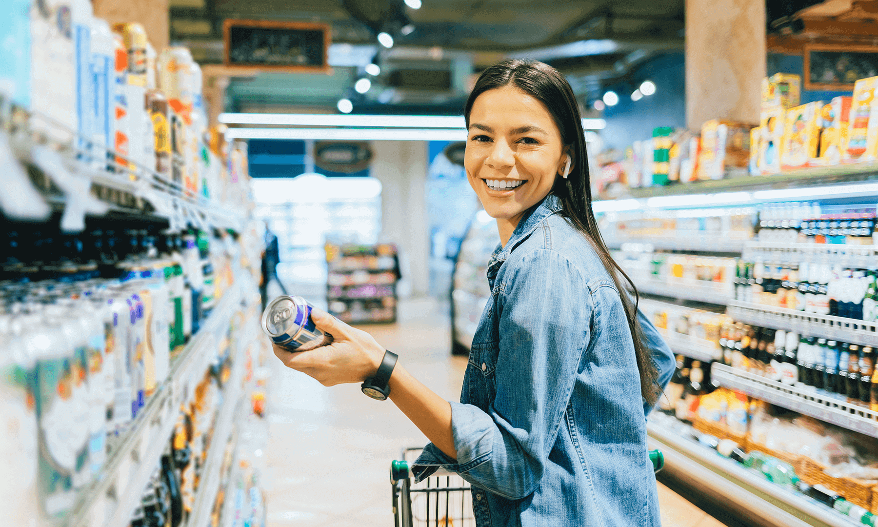 woman shopping in grocery story smiling while holding a canned drink
