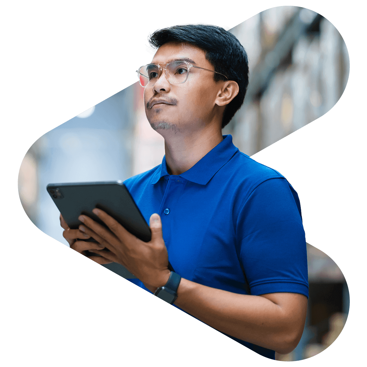 man wearing glasses and a blue shirt holding a tablet in a warehouse