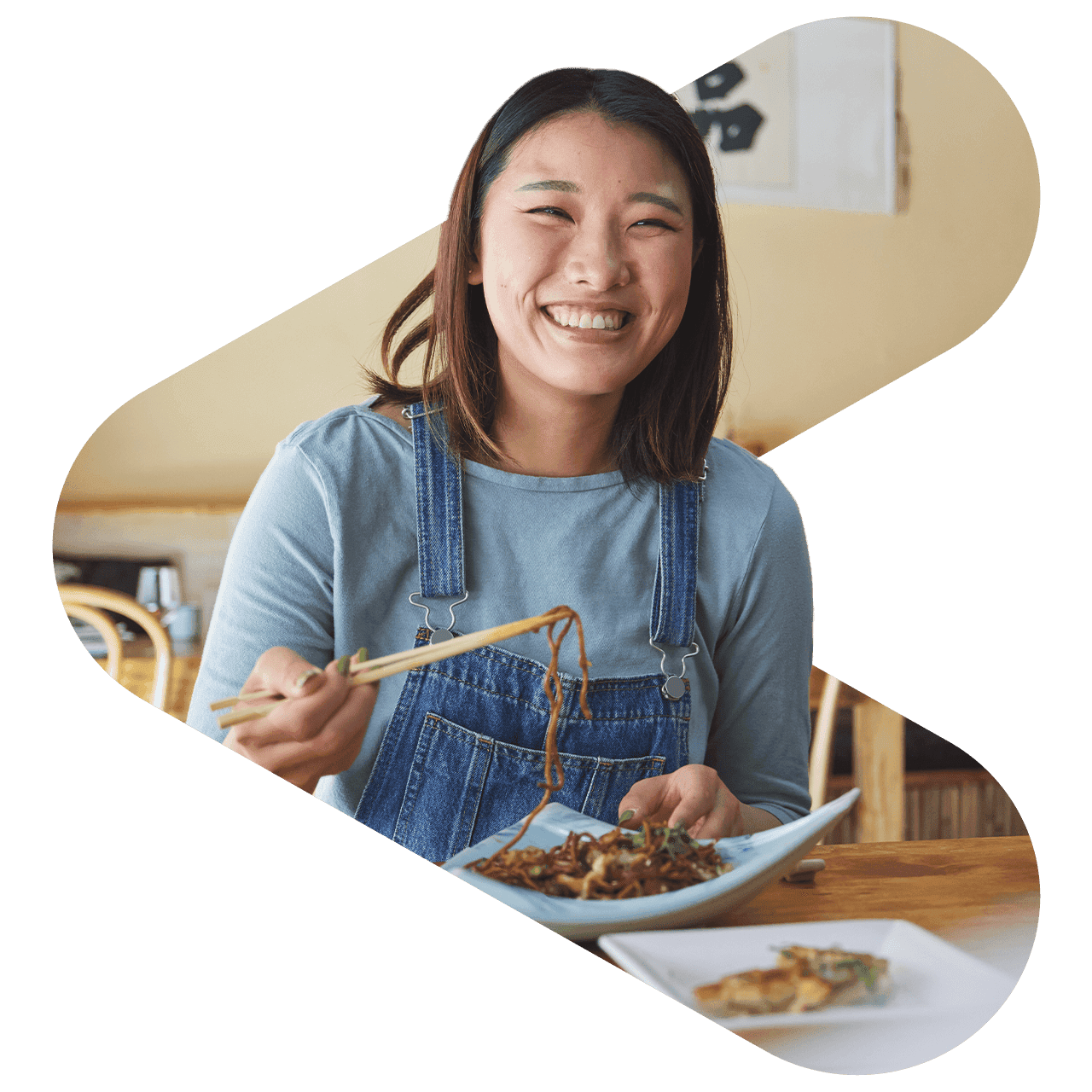 smiling woman eating noodles