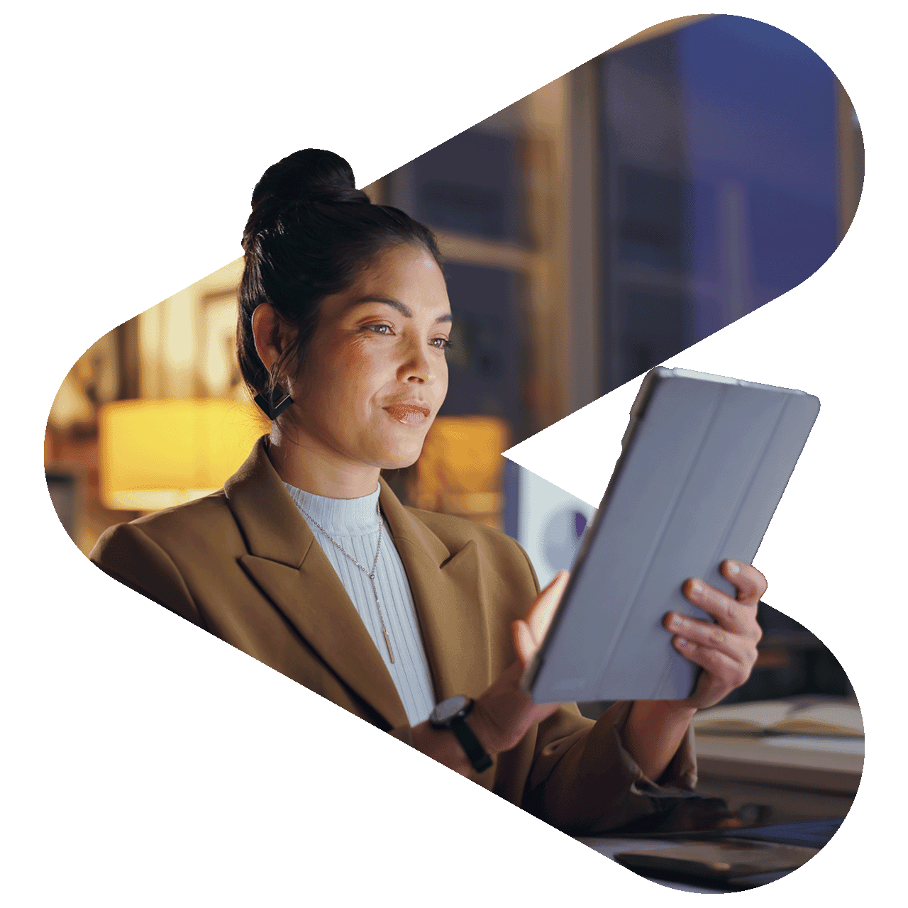 woman using tablet wearing a blazer in a dark room lit by a lamp