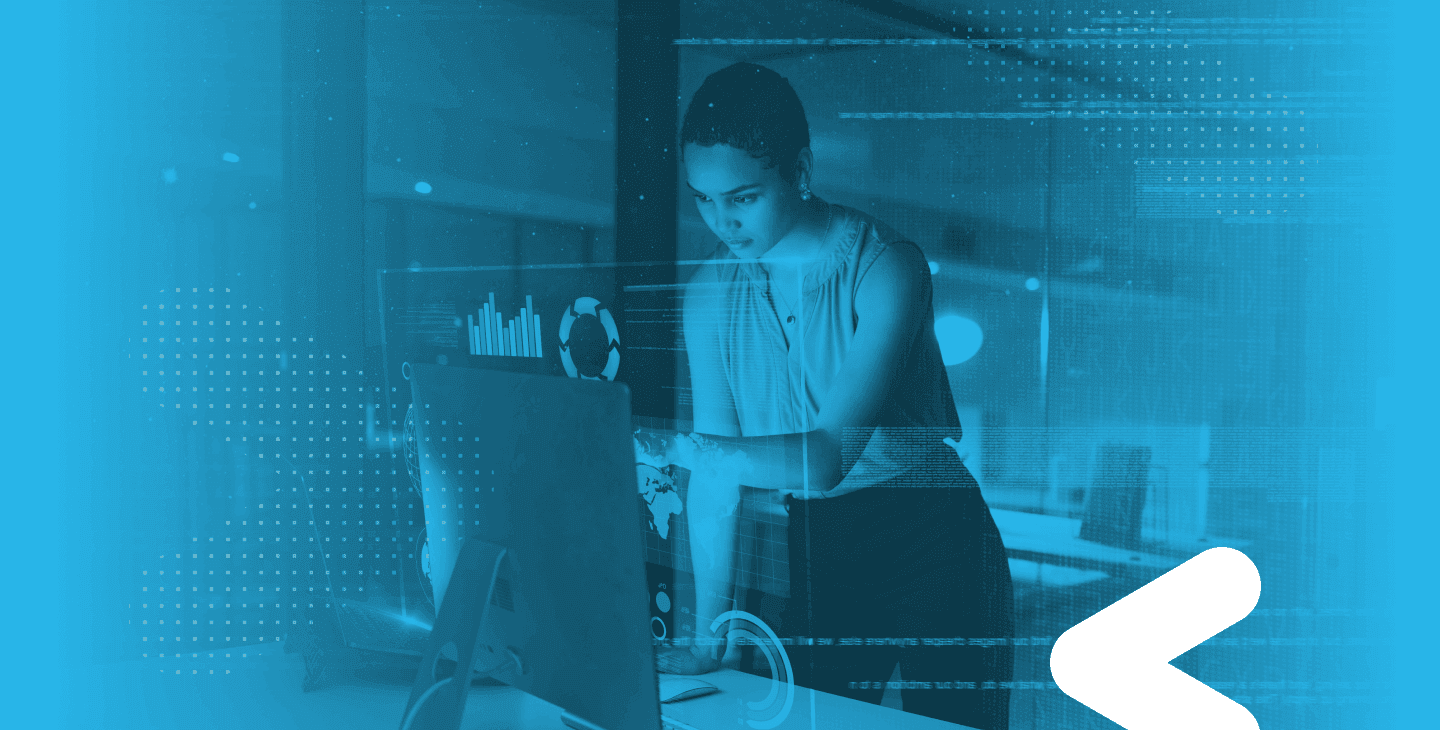 A woman standing and pointing to a computer screen with blue layover and white small chevron on the right lower corner