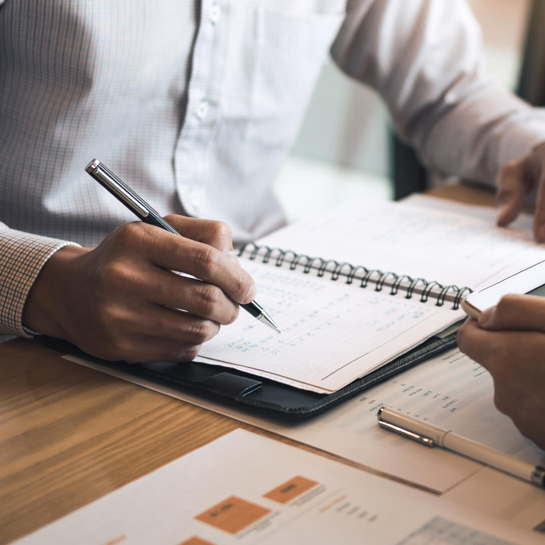  man wearing buttoned shirt holding a pen in his hand looking at planner