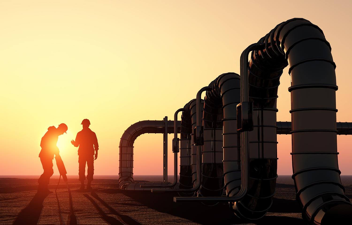 two natural gas workers working while the sun is setting behind them