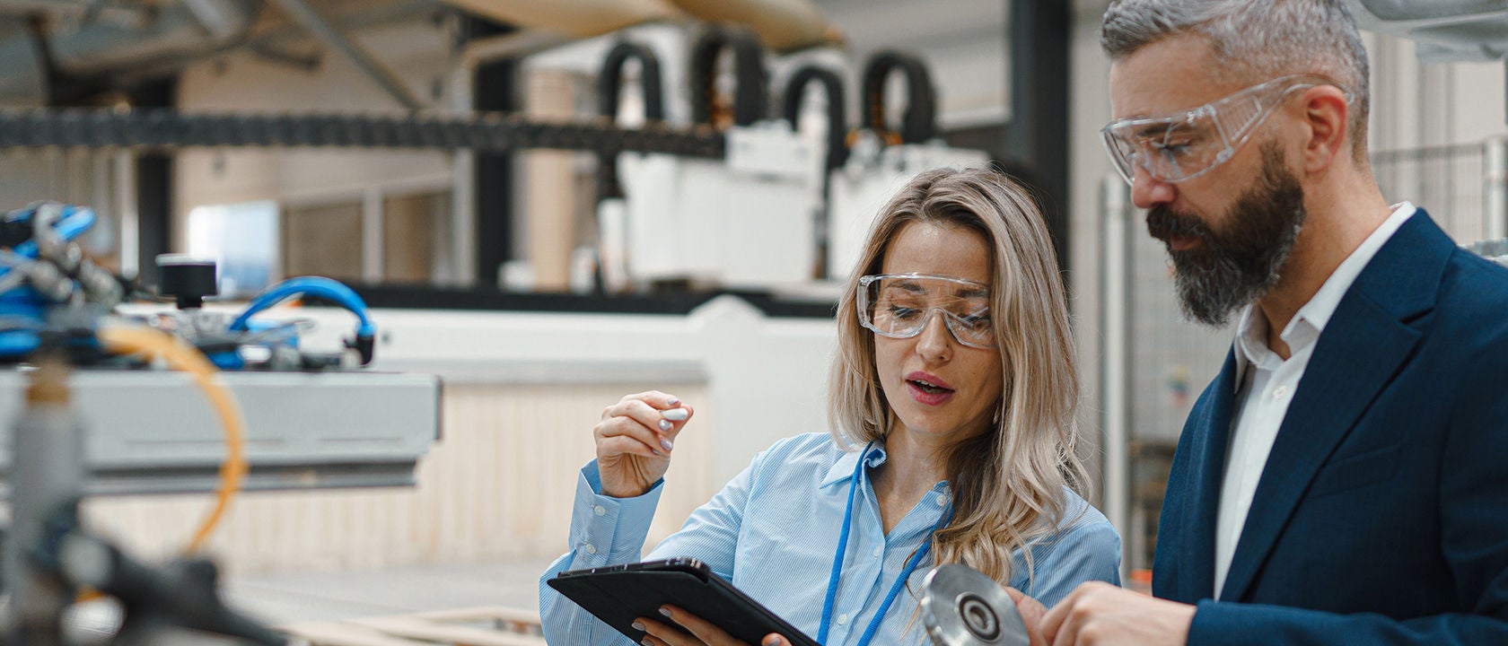 Man and woman looking at a tablet together on a factory floor