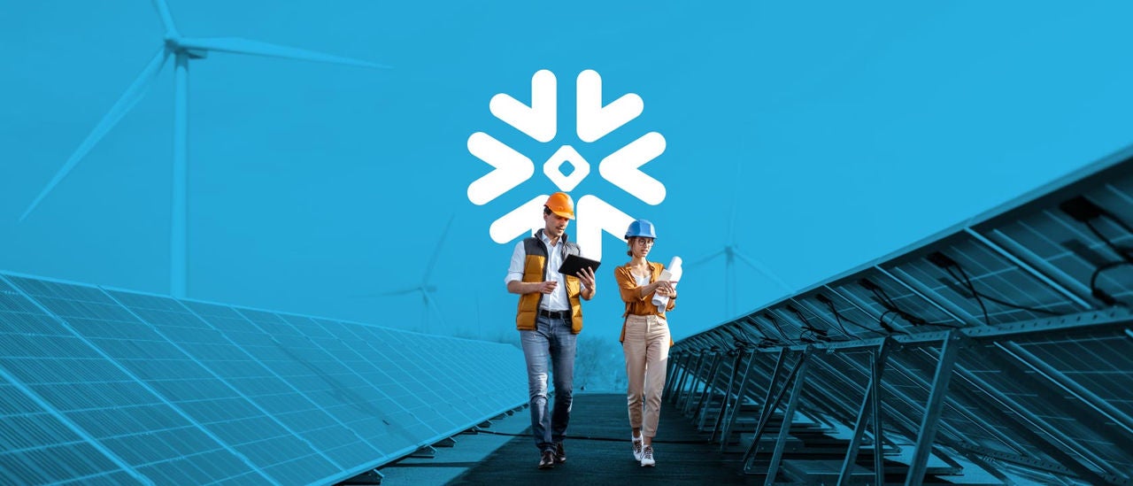 Male and female employees in hardhats and vests inspecting solar panels together.