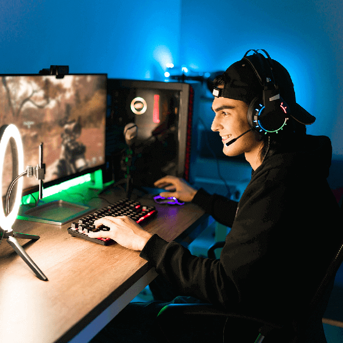 man sitting at desk wearing a gaming headset and playing a game on his monitor