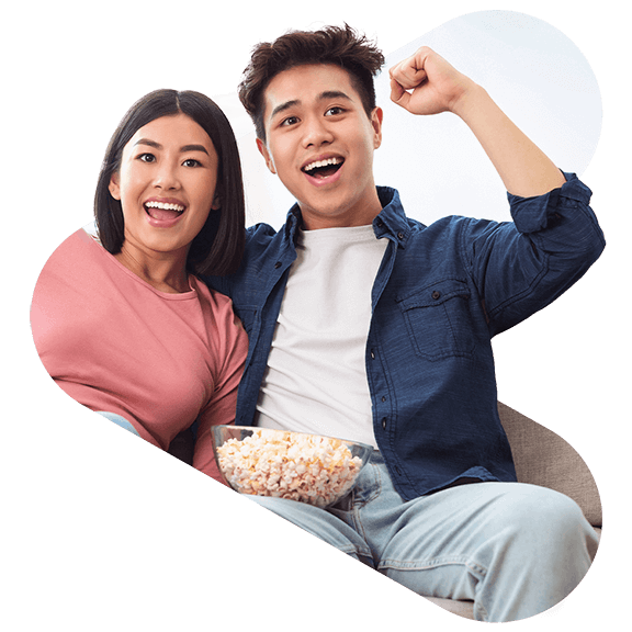 two fans sitting on a couch cheering for a game